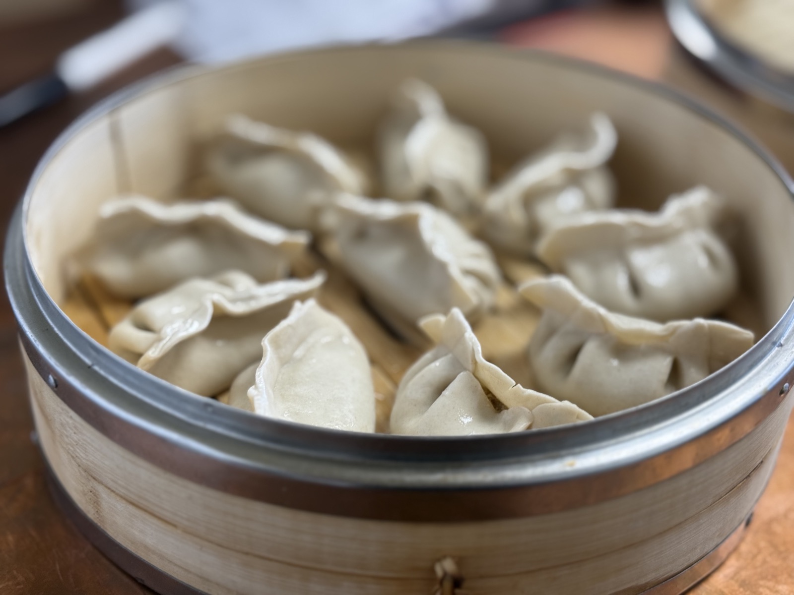Hand-folded Northern Chinese pork dumplings arranged in a bamboo steamer